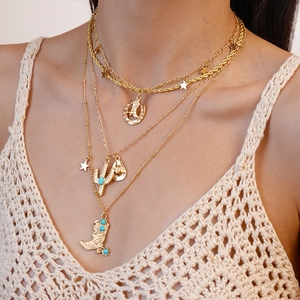 Detail of layered gold necklace with western charms like cactus and cowboy boots on model