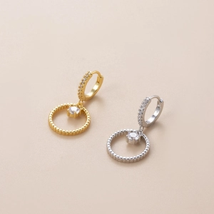 Close-up of gold and silver hoop earrings featuring star and heart zircon pendants