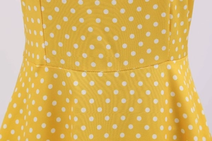 Macro shot of precise stitching on yellow polka dot dress waist seam and fabric texture