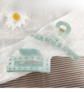 Detail of light blue acetate hair claw set with intricate rhinestone floral patterns