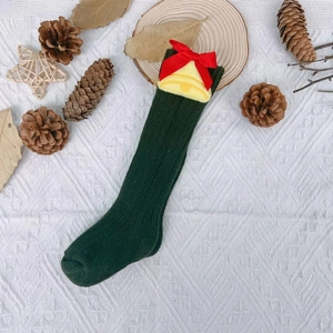 Flat lay of Christmas knit knee-high socks with red bows and bell motifs on white fabric