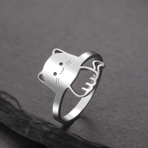 Detailed view of silver cat-shaped ring on textured dark stone with professional lighting