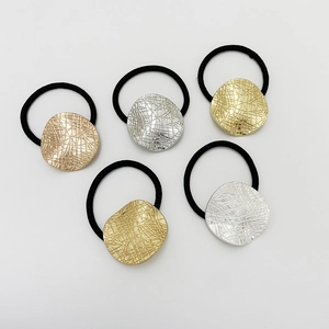 Detailed view of alloy heart charms with irregular texture on black elastic hair ties