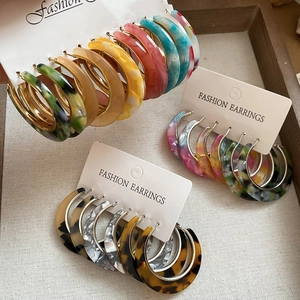 Detail view of C-shaped acetate hoop earrings with leopard and marble patterns on display