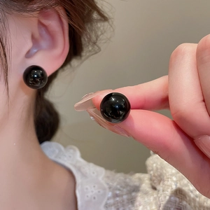 Detail shot of 10mm glossy black spherical stud earrings worn with elegant lace attire