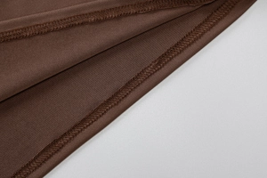 Gros plan sur un tissu en maille marron foncé avec couture overlock professionnelle