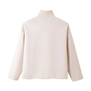 Detailed view of soft beige knit sweater featuring a ribbed turtleneck and raglan sleeves