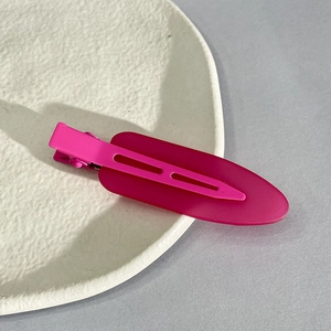 Close-up of a magenta matte seamless hair clip on a textured ceramic display plate