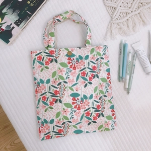 Mini sac à main en toile fleurie avec boucle dorée sur fond texturé blanc
