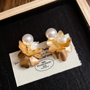Macro shot of gold vintage flower earrings with freshwater pearls on a black display box
