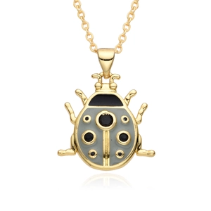 Macro shot of gold ladybug pendant featuring gray enamel and black dotted detail