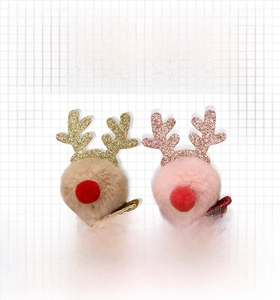Détail de pinces à cheveux renne en peluche avec bois scintillants et pompons festifs