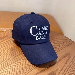 Classic navy blue cotton baseball cap with white embroidery on a wooden surface