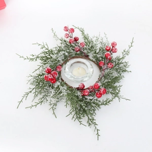 Close-up of frosted Christmas candle ring with pine branches, red berries, and glass holder