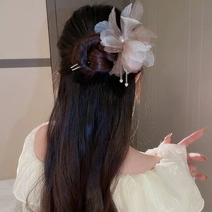 Détail d'épingle à cheveux fleur en tissu rose avec glands de perles dans un chignon