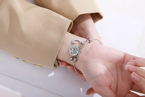 Silver stainless steel star and moon charm bracelet displayed on a model's wrist
