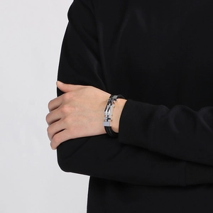 Dettaglio di un bracciale da uomo in pelle nera intrecciata con chiusura in acciaio