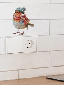 Détail d'un joli autocollant d'oiseau de Noël avec bonnet bleu au-dessus de l'interrupteur