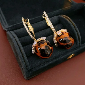 Macro shot of gold earrings with leopard print beads in a velvet jewelry box