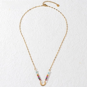 Detail of gold beaded necklace with colorful spheres and bohemian sunburst pendant