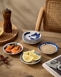 Detail of Japanese ceramic cat sauce dishes on a wooden table with kitchen props