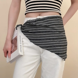 Detail of a black and white striped cotton-linen scarf tied around the waist as a belt accessory