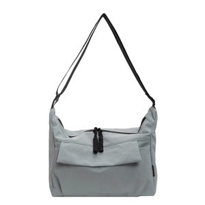 Close-up of light blue nylon tote bag with black woven zipper cords and adjustable strap