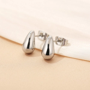 Polished silver teardrop stud earrings in stainless steel on silk fabric background