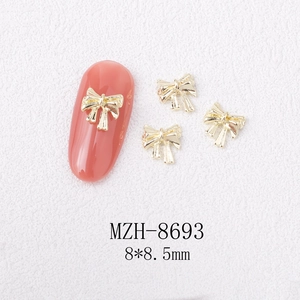 Macro shot of 8x8.5mm golden bow alloy nail charms with fine texture on pink manicure