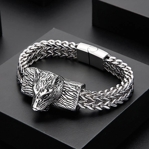 Detailed view of silver stainless steel wolf head bracelet with wheat chain on dark base