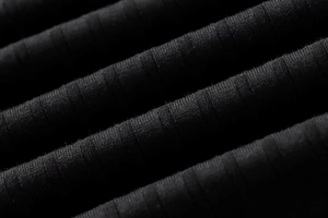 Primer plano del tejido de punto acanalado negro con textura vertical y elasticidad premium