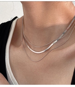 Close-up of triple-layered 925 silver snake bone necklace on a female neck