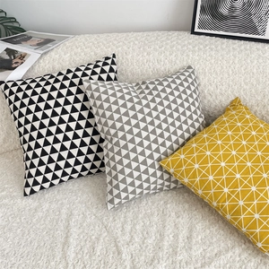 Detailed view of geometric pattern cushion covers on a textured white sofa setting