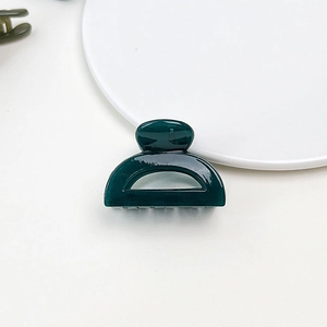 Macro view of a dark green jelly resin hair claw clip showing glossy finish and texture