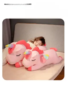 Detailed view of pink plush rainbow unicorn lying on cozy grey bedding as home decor