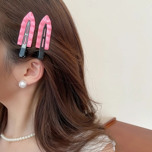Pink minimalist triangle hair clips with wavy texture worn by model with pearls