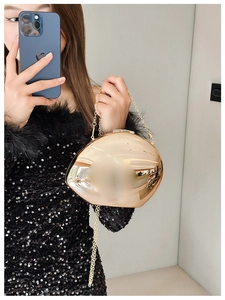 Detailed close-up of golden mirror finish evening bag with elegant metal chain strap