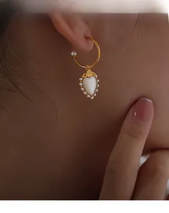 Detail of gold heart earring with mother-of-pearl inlay and delicate rose flower