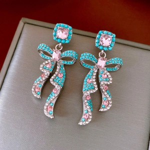 Detail of vintage bow earrings with pink crystals and turquoise beads on a gray box