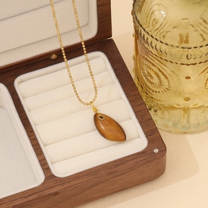 Goldene Kugelkette mit tropfenförmigem Tigerauge-Anhänger in einer Schmuckschatulle