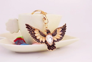 Detail of a vintage golden eagle keychain with rhinestones and enamel wings in a cup
