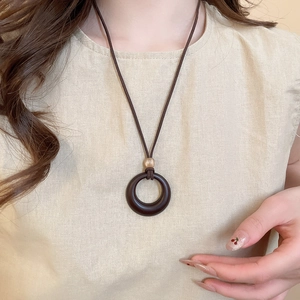 Close-up of a vintage resin pendant necklace with wax cord on a model wearing beige linen