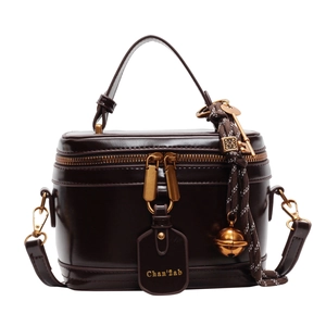 Classic dark brown box bag with a top handle and vintage charms on a white background