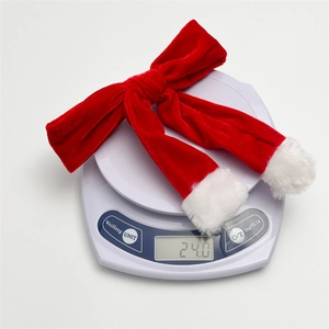 Red velvet Christmas bow hair clip with white faux fur trim on a digital weight scale