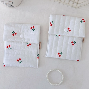 Close-up of quilted cotton pouches featuring red cherry prints and white snap fasteners