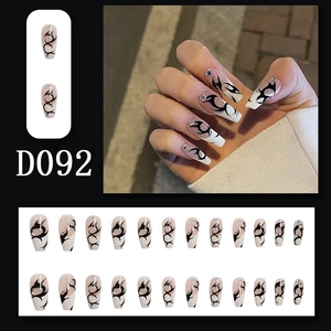 Detail of long coffin press-on nails with black flame patterns and rhinestone accents