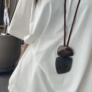 Minimalist long geometric pendant necklace with dark brown resin accents on a cord