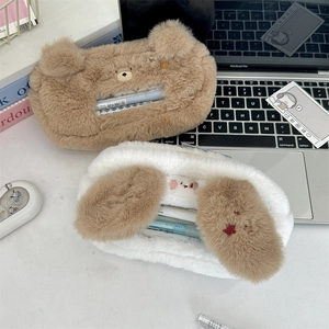 Detail of plush animal pencil cases with transparent window and embroidery on a desk