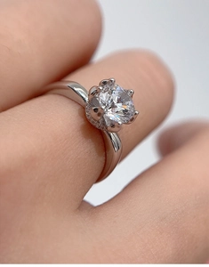 Detailed macro view of a six-prong silver engagement ring featuring a one-carat moissanite