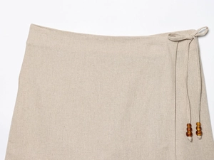 Detail of oat beige linen top with waist tie and dark brown polished wooden beads